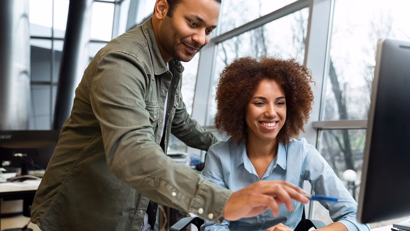 Two individuals smiling while staring at a screen