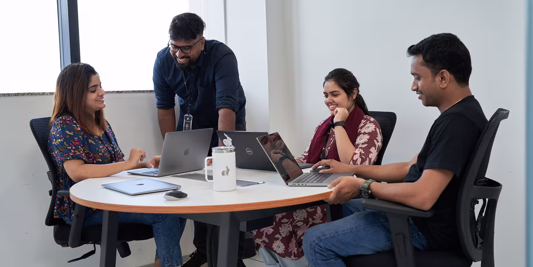 Group of 4 individuals smiling while working